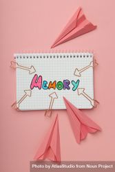 Vertical composition of notepad with “memory” written in colorful markers with paper planes 43W6j4