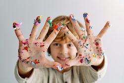 Smiling boy showing palms with stuck colorful confetti