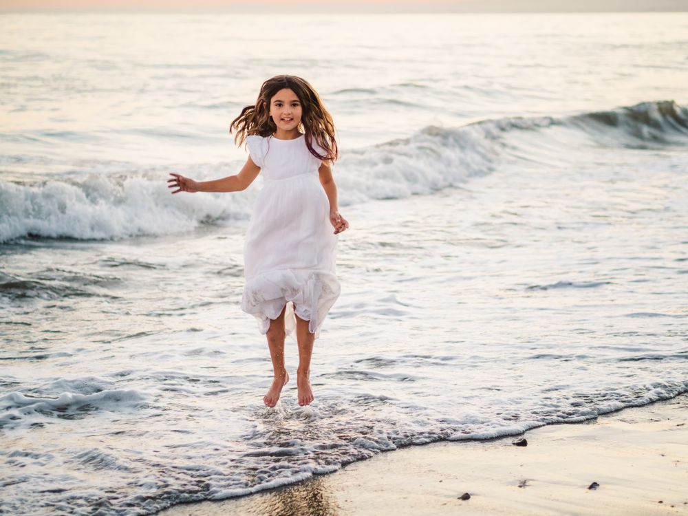 Excited girl running along beach in daylight