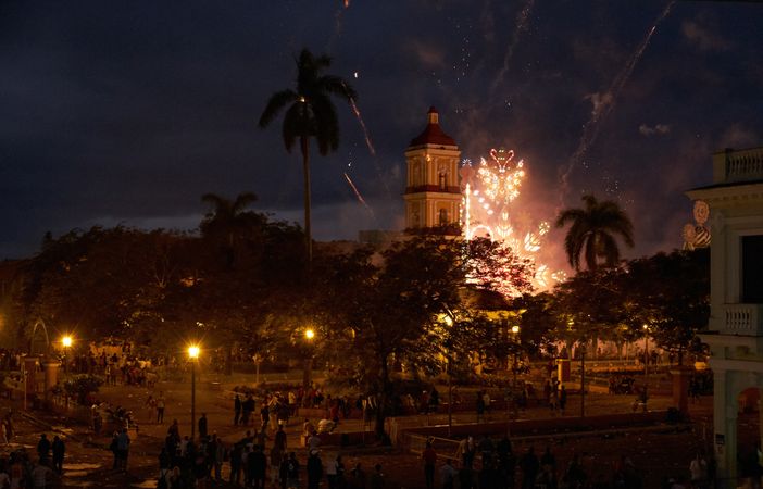 People walking on square at night with fireworks in sky