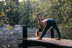 Woman in sportswear doing yoga outdoors near a lake