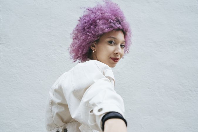Stylish woman with pink hair looking at camera