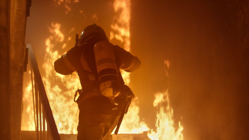 Firefighter with an oxygen cylinder runs up the stairs