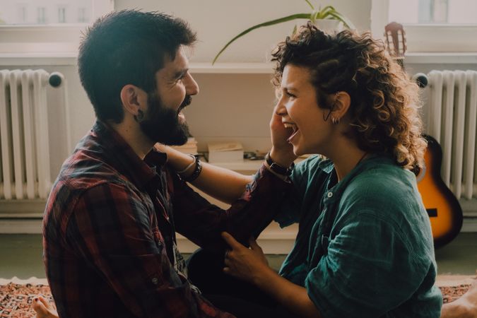 Loving couple embracing while sitting on apartment floor