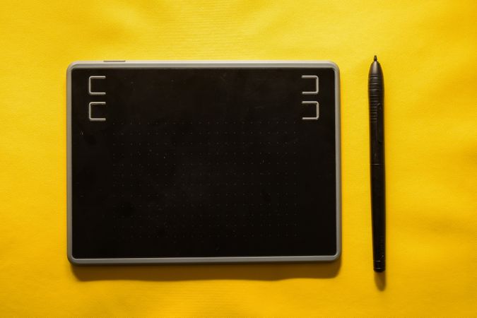 Digital tablet and stylus on yellow background