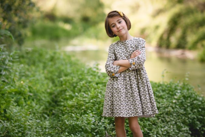 Little girl standing by river with her arms crossed