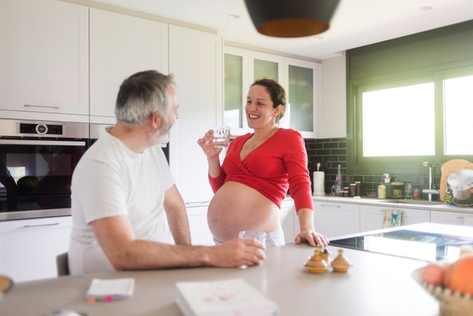 Happy white couple, pregnant woman with husband in kitchen