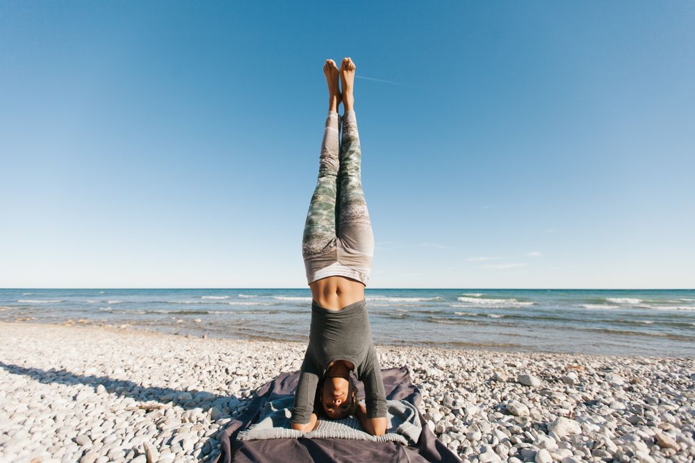 Sportive woman performing yoga posture in the beach
