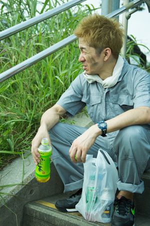 Exhausted man in work suit sitting on staircase holding a green bottle