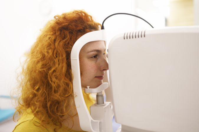 Red haired woman in machine in optometrist office