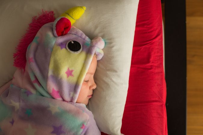 Girl in unicorn pajama sleeping in bed
