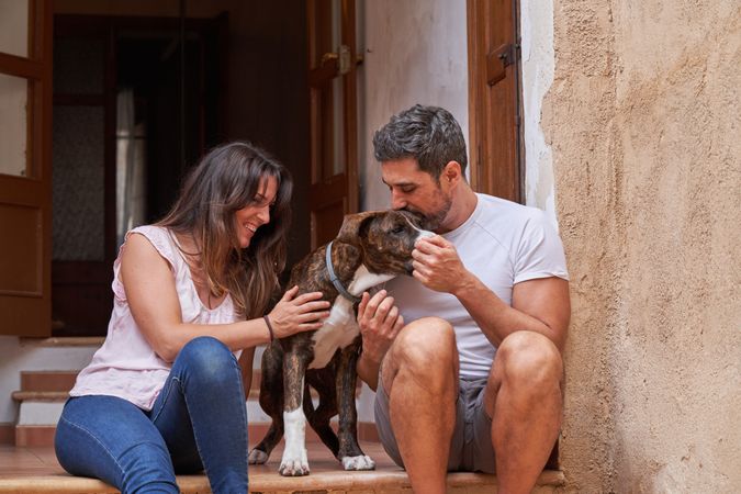Loving couple petting dog on porch