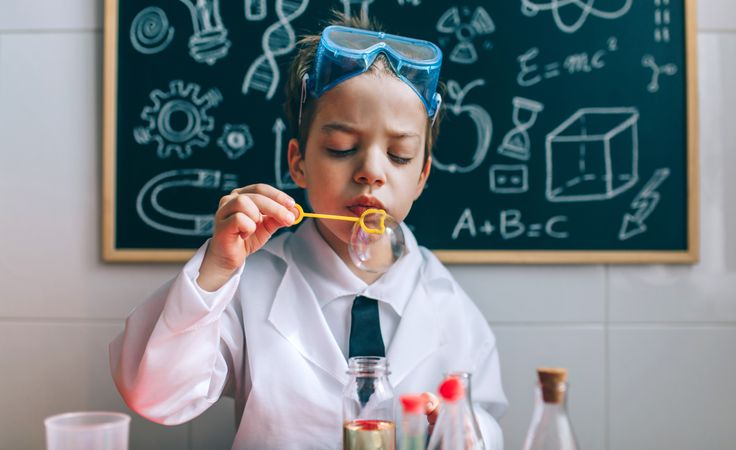 Boy playing with chemistry game blowing bubbles in lab