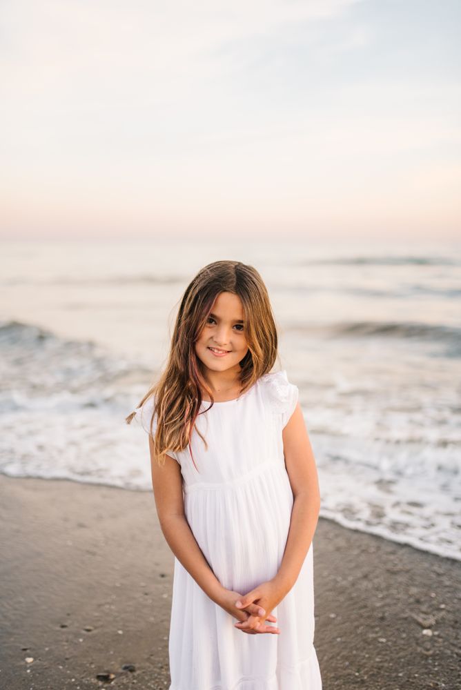 Smiling girl standing on seaside among waves
