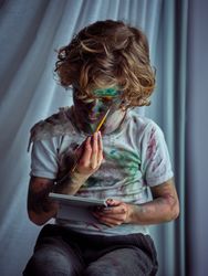 Boy looking at mirror and painting face