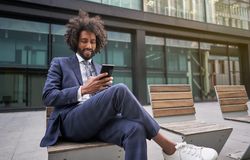 Joyful man in suit sitting outside and messaging