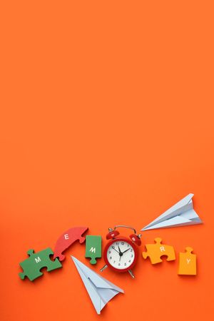Vertical composition of puzzle pieces spelling “memory” on orange background with copy space