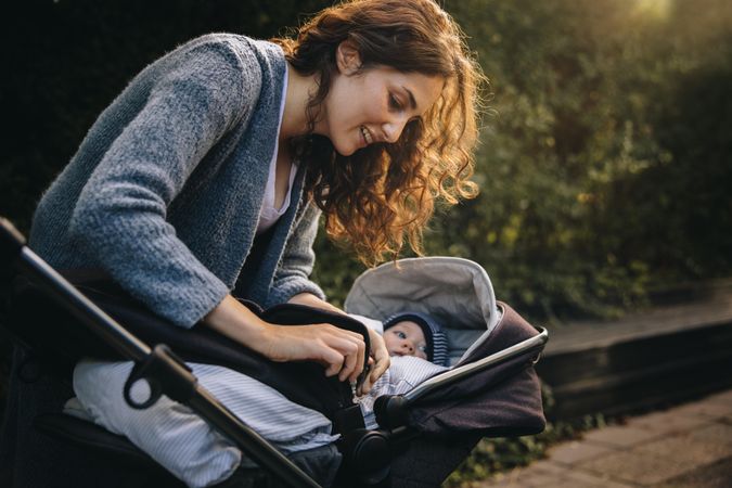 Woman fastening belt on baby in stroller