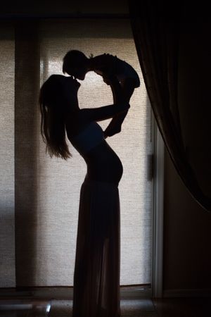 Silhouette of pregnant mother holding a baby