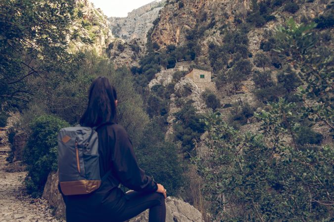 Woman traveler with backpack sitting on hill
