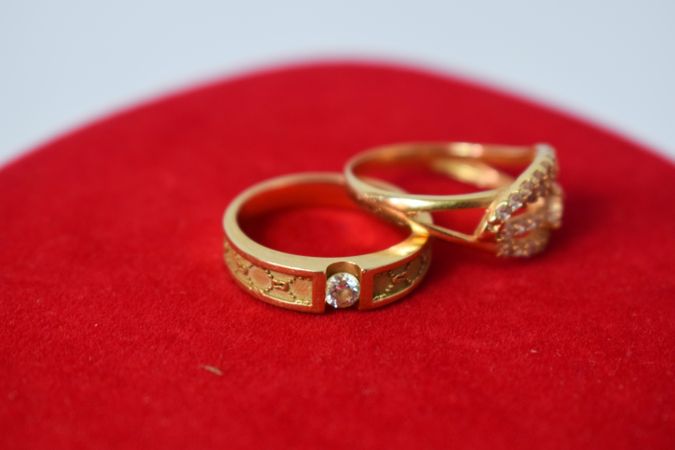Two diamond gold wedding rings on red cloth with copy space