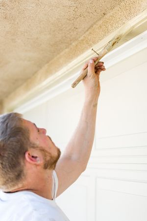 Professional Painter Cutting In With Brush to Paint Garage Door Frame