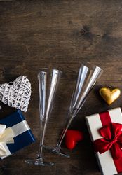 Top view of two glass champagne flutes with gifts and heart ornaments with copy space