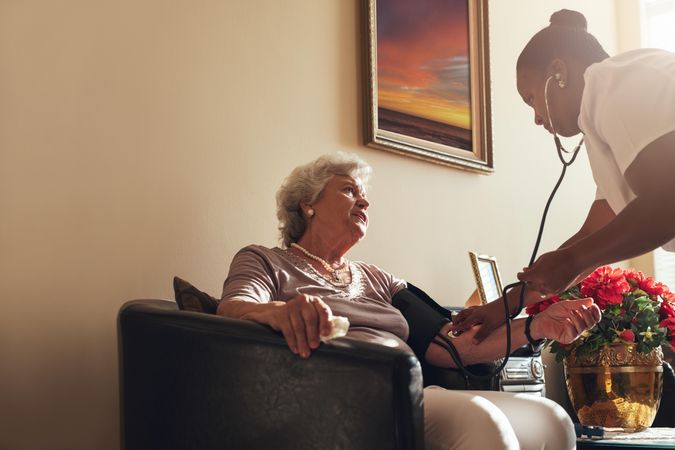 Home healthcare nurse checking blood pressure of older woman