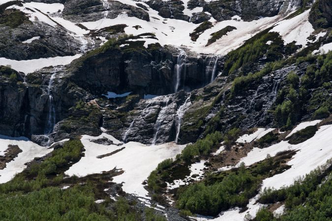 Snowy mountains with cascading waterfalls and green vegetation