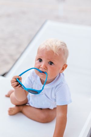 Blond baby playing with sunglasses