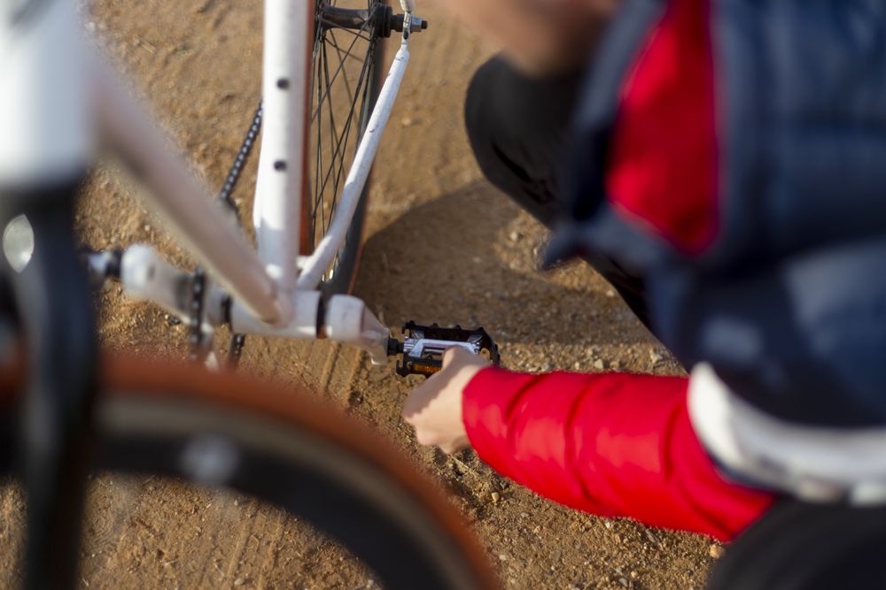 Man repairing his bicycle outdoors on dirt road