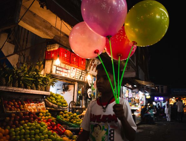 Young Indian boy selling balloons in street market at night in Mussoorie India