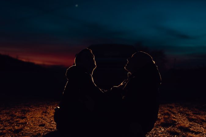 Men hugging and sitting on ground on field at night