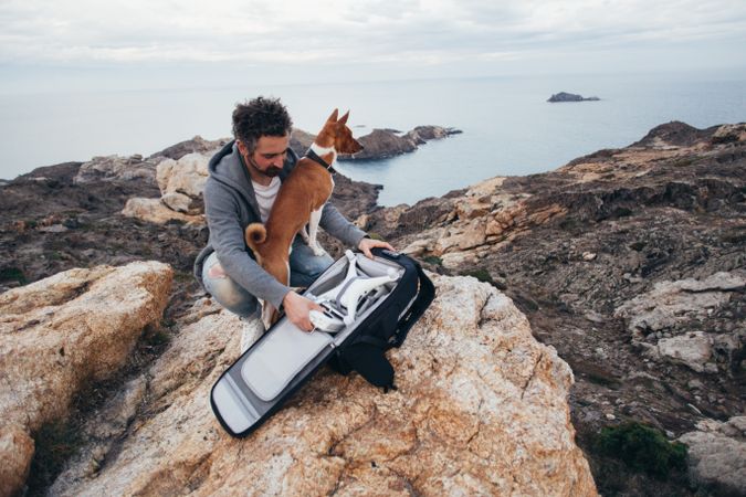 Man opening bag with drone equipment on a cliff