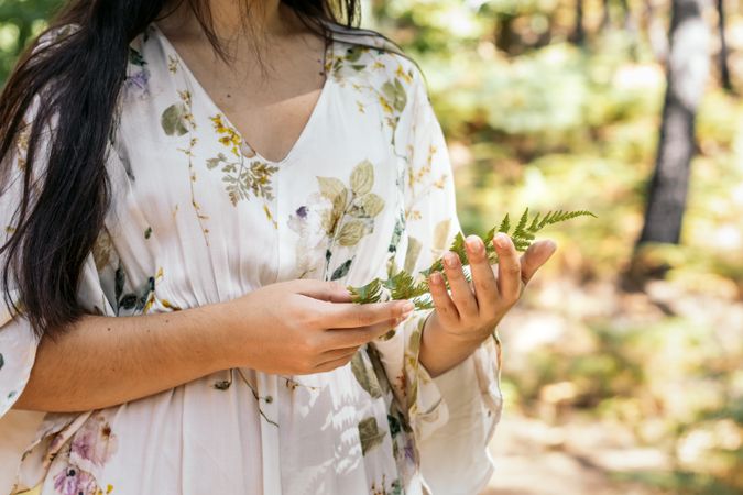 Young woman touching leaves in the forest