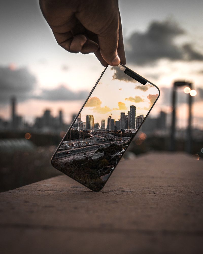 Person holding phone taking photo of city
