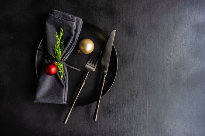 Christmas table setting with dark cutlery, plate and table with ornaments