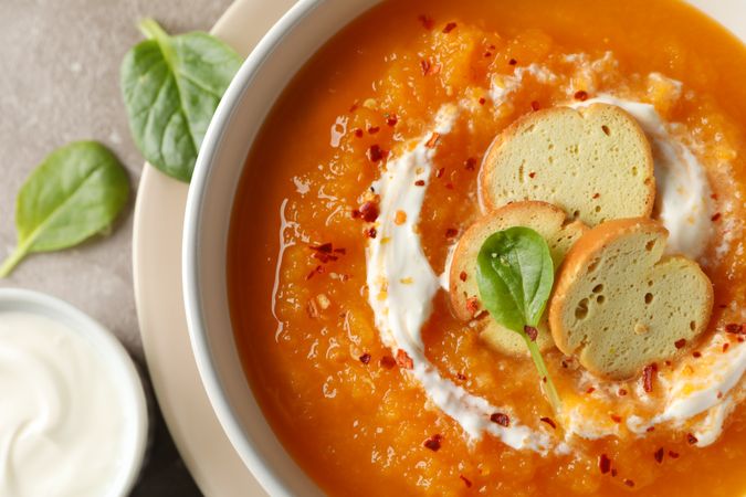 Close up top view of bowl of pumpkin soup on marble counter