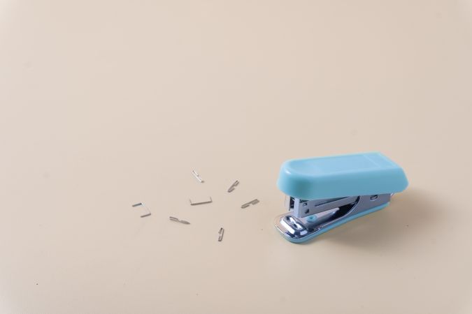 A desktop stapler surrounded by scattered staples on a table