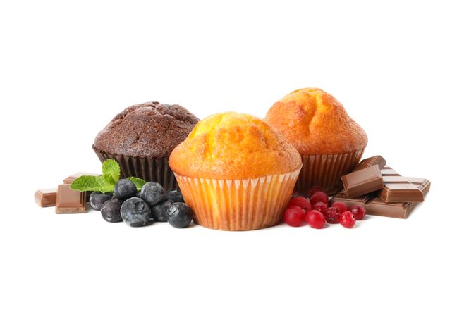 Muffins, berries and chocolate isolated on light background