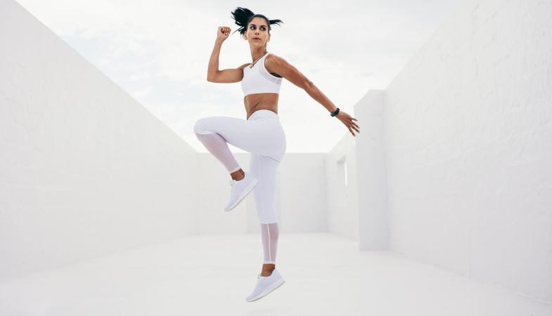 Slender woman in fitness wear performing jump exercise