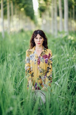 Serious brunette female looking at camera in field of tall grass