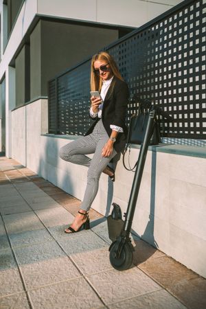 Businesswoman with mobile and her scooter next