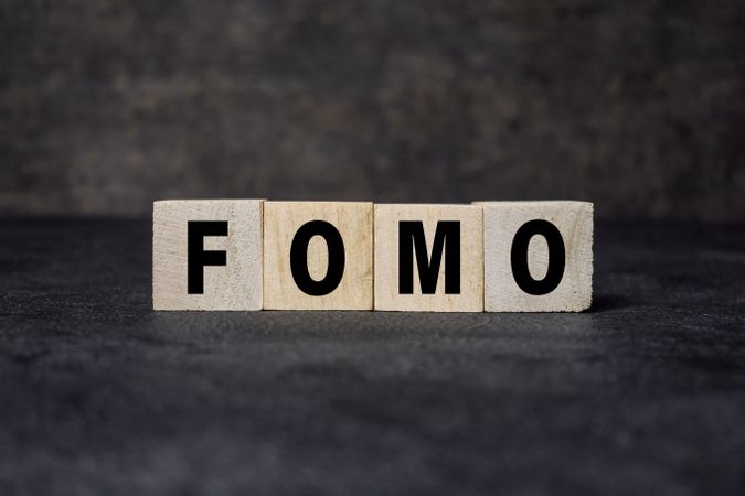 fomo symbol or fear of missing out text on wooden blocks on dark background