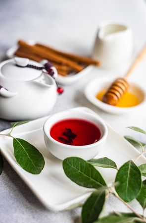 Cup of fragrant red tea from pot served with honey dipper