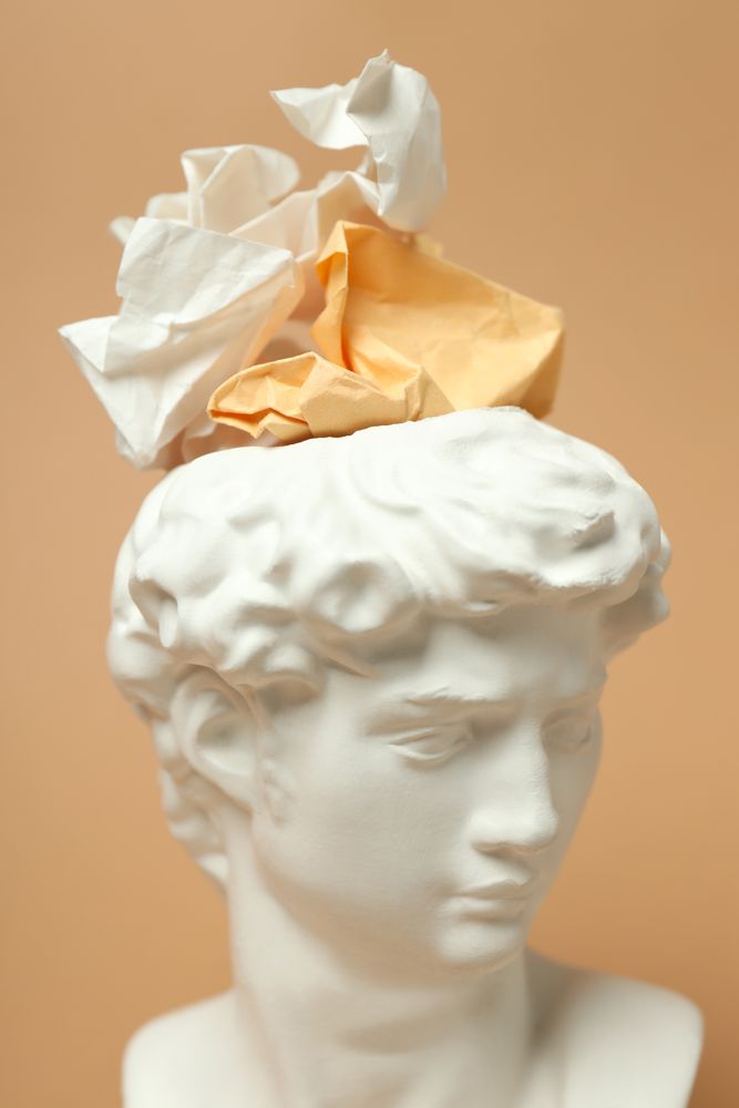 Marble bust with crumpled paper on brown background, vertical close up