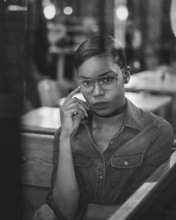 Monochrome image of woman in glasses as seen through window