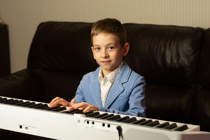 Young boy in blue blazer playing the piano