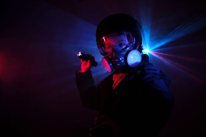 Kid in respirator shining flashlight in darkness