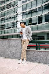 Man using smartphone leaning against wall